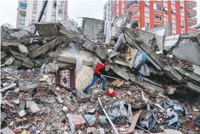  ?? ?? A man walks among rubble as he searches for people in a destroyed building Monday in Adana, Turkey. A powerful quake has knocked down multiple buildings in southeast Turkey and Syria, killing thousands. (AP Photo/Khalil Hamra)