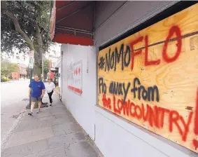  ?? MIC SMITH/ASSOCIATED PRESS ?? Michael and Polly Long walk past a sign Thursday in Charleston, S.C., asking for Hurricane Florence to spare the region.