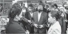  ?? KEVIN RICHARDSON/BALTIMORE SUN ?? Gov. Larry Hogan, center, along with first lady Yumi Hogan, right, talk with Mickey Kim, left, owner of Honey Pig Restaurant in Ellicott City. The governor and Howard County Executive Calvin Ball, background, listened to the business owners’ concerns about the rise in anti-Asian violence and discrimina­tion during a visit Monday.