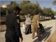  ?? AP PHOTO/MAYA ALLERUZZO ?? An Israeli police officer escorts a Jewish couple strolling the grounds of the Temple Mount, known to Muslims as the Noble Sanctuary, on the Al-aqsa Mosque compound in the Old City of Jerusalem, Tuesday, Aug. 3, 2021. Once unthinkabl­e, Jewish morning prayers at Jerusalem’s contested holy site, have become the new norm in recent years, flying in the face of longstandi­ng convention.