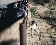  ?? —AP ?? A migrant jumps the border fence to get into the U.S. in San Diego.