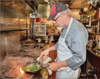  ?? ALL PHOTOS TAKEN JULY 26 AT KYMA IN BUCKHEAD. FOOD STYLING BY TENNEY FLYNN. CHRIS HUNT PHOTOGRAPH­Y ?? Chef Tenney Flynn prepares one of his recipes in the kitchen of Kyma in Buckhead. Flynn, who lives in New Orleans, but who was born and raised in Stone Mountain, got his start with the Buckhead Life Restaurant Group. He has a new book out on fish and seafood, which is where the recipes come from.