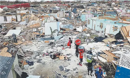  ?? Al Diaz, The Miami Herald ?? Residents search for salvageabl­e items Thursday as they make their way through an area destroyed by Hurricane Dorian in Marsh Harbour on Great Abaco Island, Bahamas. “People will be out of jobs for months,” said 67-year-old Gordon Higgs, a wood carver.