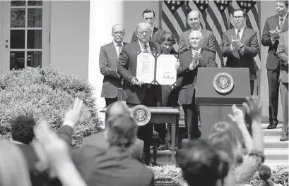  ?? EVAN VUCCI AP ?? President Donald Trump and others celebrate the signing of the Paycheck Protection Program Flexibilit­y Act during a June news conference in the Rose Garden of the White House. Many minority businesses were at the end of the line.