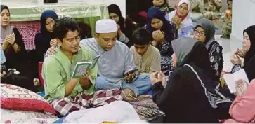  ??  ?? MOHAMAD Hakim memimpin bacaan doa dan tahlil di samping jenazah Nur Rizqi yang terlibat dalam kemalangan.