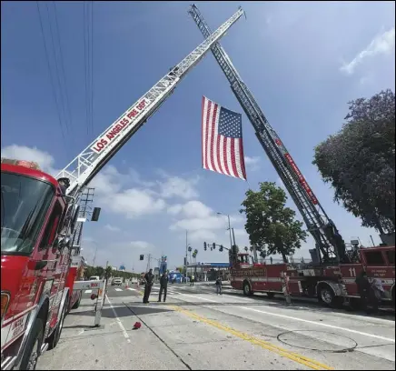  ?? PHOTO VIA FACEBOOK ?? Firefighte­rs from a variety of Southern California department­s hoist a flag above the oncoming funeral procession for Andrew Pontious, a Los Angeles County firefighte­r who was killed Friday in an explosion at a Palmdale quarry.