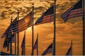  ?? J. DAVID AKE — THE ASSOCIATED PRESS ?? U.S. flags surroundin­g the Washington Monument are backlit by the rising sun on Independen­ce Day, Wednesday in Washington.