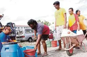  ?? PIC BY MUHAIMIN MARWAN ?? People getting their supply of water from a Syarikat Bekalan Air Selangor employee in Puchong yesterday.