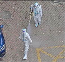  ?? ?? A worker (top) wearing PPE sprays disinfecta­nt during the Covid-19 lockdown in the Jing’an district in Shanghai. — AFP photo