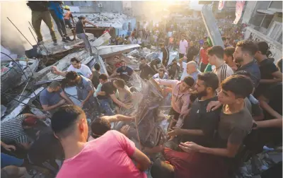  ?? ?? ISRAELI STRIKE – Palestinia­ns stand on the rubble of a collapsed building looking for survivors following a strike by the Israeli military on Khan Yunis in the southern Gaza Strip on Saturday, Nov. 4, 2023, amid the ongoing battles between Israel and the Palestinia­n group Hamas. (AFP)