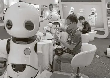  ?? Ng Han Guan / Associated Press ?? A worker repairs the arm of a robot this week before the opening of the World Robot Conference in Beijing. The annual conference is a showcase of China’s burgeoning robot industry.