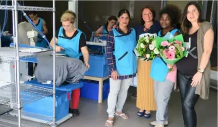  ?? FOTO JAA ?? Elisabeth Mina (tweede van rechts) is dankzij OCMW-medewerkst­er Maja Imamovic (rechts) de honderdste werknemer van Alexandra Van Tongelens (derde rechts) strijk- en poetsbedri­jf. Dat wordt gevierd met bloemen.