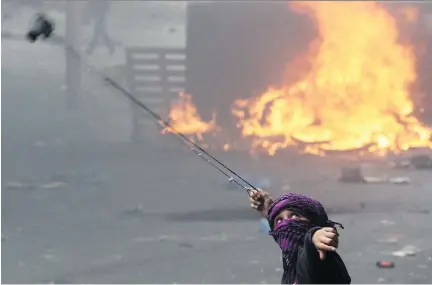  ?? HAZEM BADER/AFP/GETTY IMAGES ?? A Palestinia­n youth slings a stone toward Israeli security forces in the West Bank town of Hebron on Tuesday.