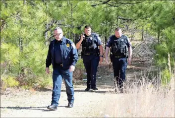  ?? ♦ Doug Walker ?? Rome Police Maj. Rodney Bailey (left) returns from a trail behind Riverside Toyota where a man was shot in the head early Monday. The trail leads between the auto dealership and the Callier Forest Apartments at 131 Dodd Blvd.