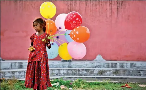  ?? REUTERS ?? A young girl sells balloons by the Yamuna River as devotees carrying idols of the Ganesh, the deity of prosperity, immerse the idol on the last day of the ten-day-long Ganesh Chaturthi festival in Delhi, on Thursday.