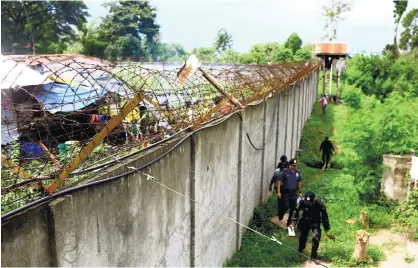  ?? (AP FOTO) ?? MASSIVE JAILBREAK. Policemen patrol outside the walls of the North Cotabato District Jail in Kidapawan city, Cotabato Province, southern Philippine­s, after a massive jailbreak early Wednesday, Jan. 4, 2017, following an attack on the facility by over...