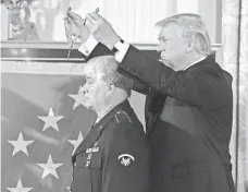  ?? ALEX WONG, GETTY IMAGES ?? Donald Trump presents the first Medal of Honor of his presidency to former Army specialist James McCloughan.