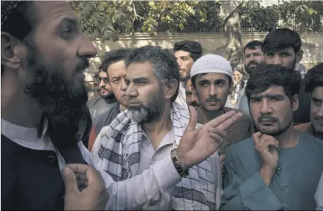  ?? FELIPE DANA — THE ASSOCIATED PRESS ?? A member of the Taliban, left, talks to Afghans gathering outside a government passport office recently re-opened after Taliban announced they would be issuing a backlog of applicatio­ns approved by the previous administra­tion in Kabul, Afghanista­n Oct. 6.