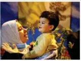  ?? Reuters ?? ■A woman standing outside holds a child as she listens as Pope Francis holds a Mass at the Chaldean Cathedral of ‘Saint Joseph’ in Baghdad.