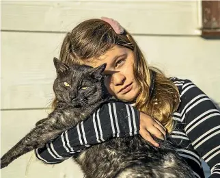  ?? BRADEN FASTIER/STUFF ?? Nine-year-old Stella McIvor with the family’s remaining cat, Theo. Their other cat Milly died from a bullet wound.