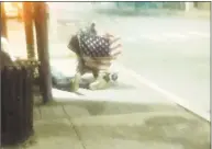  ?? James Walker / Hearst Connecticu­t Media ?? A mentally ill man sleeps on the ground near a bus stop on John Street in downtown Bridgeport. An American flag is draped across his shopping cart.