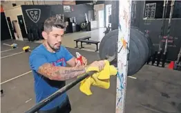  ?? JOHN MCCALL/SOUTH FLORIDA SUN SENTINEL ?? Coach Johan Vasquez sanitizes equipment at CrossFit Wynwood in Miami on Monday. Miami-Dade County will close restaurant­s and gyms after a spike in coronaviru­s cases.