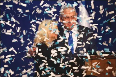  ?? (AP/Oded Balilty) ?? Israeli Prime Minister Benjamin Netanyahu, accompanie­d by his wife, Sara, addresses his supporters Monday in Tel Aviv after the first exit poll results were released.