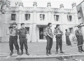  ??  ?? ON GUARD: Police stand in front of a mosque and school dormitory that were damaged in a fire in Yangon. — Reuters photo