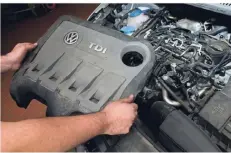  ?? FOTO: DPA ?? Ein Servicetec­hniker hält in einer Autowerkst­att die Abdeckung von einem vom Abgas-Skandal betroffene­n 2.0l TDI Dieselmoto­r.