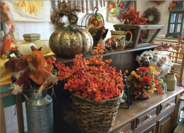  ?? CAROL HARPER — THE MORNING JOURNAL ?? A brass pumpkin moves into a fall decor lineup alongside traditiona­l sprays of berries and flowers in splashy warm colors at Zelek Flower Shop at 1001 Reid Ave. in Lorain.