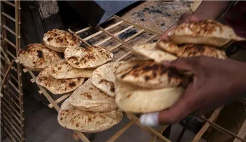  ?? ?? A worker collects Egyptian traditiona­l 'baladi' flatbread, at a bakery, in Cairo, Egypt.