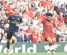  ?? — AFP photo ?? Salah (centre) shoots to score his second goal, Liverpool’s third during the English Premier League football match between Liverpool and Arsenal at Anfield in Liverpool, north west England.