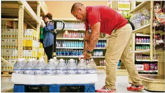  ?? DUSTIN SAFRANEK / FOR AMERICANST­ATESMAN ?? Jesse Delacruz, grocery manager at the H-E-B on Oltorf Street and South Congress Avenue in Austin, works Friday to keep up with a surge in demand for bottled water. “We are having a rush on water,” Delacruz said.