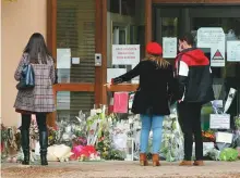  ?? AP ?? People stand by flowers laid outside the school where slain history teacher Samuel Paty, 47, was working.