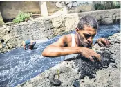  ??  ?? Searching for traces of gold pieces earrings, rings and other small jewels at the bottom of the waters of the polluted Guaire River in the capital, Caracas