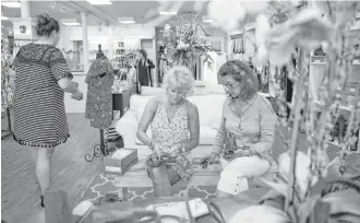  ?? Michael Ciaglo / Houston Chronicle ?? Pam Slack, center, from Florida, tries on sandals as she sits with her friend Judy Patane, a Galveston local, at the Head to Footsies boutique on the Strand in Galveston.