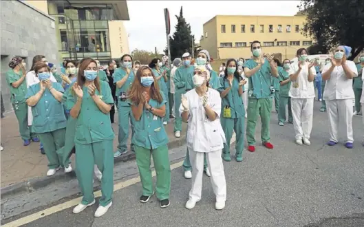  ?? ÁNGEL DE CASTRO ?? Un grupo de sanitarios aplaude en la entrada del hospital Miguel Servet de Zaragoza.