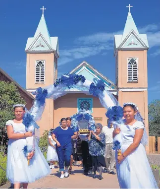  ?? GREG SORBER/JOURNAL ?? Fatima Trujillo, left, and Jovanna Montoya, right, carry an arch as, from left, Erica Cordova, Margaret Montoya, Ruth Lopez and Richard Lopez carry an image of San Lorenzo from the Santuario de San Lorenzo into Our Lady of Sorrows Catholic Church on...