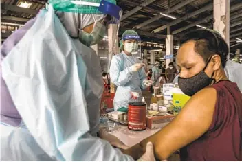  ?? ADAM DEAN THE NEW YORK TIMES ?? A man receives a dose of COVID-19 vaccine last month in Bangkok, Thailand. Countries struggling to obtain vaccines from wealthier countries may be able to make NVD-HXP-S for themselves or buy it at low cost.