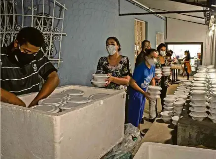  ?? Bruno Santos/Folhapress ?? Voluntário­s do Batuque de Panela separam marmitas para distribuir em São Paulo