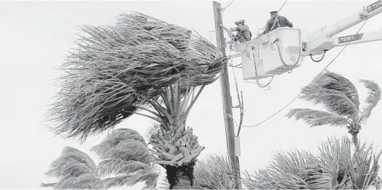  ?? MIKE STOCKER/SOUTH FLORIDA SUN SENTINEL ?? Power crews work on lines in Jensen Beach as residents wait as the slow moving Hurricane Dorian continues to churn offshore.