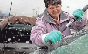  ?? ASSOCIATED PRESS ?? Mary Zinser of Imperial, Mo., chisels a thick layer of ice off her windshield in nearby Arnold on Friday. Freezing rain coated roads, causing numerous accidents and closures.