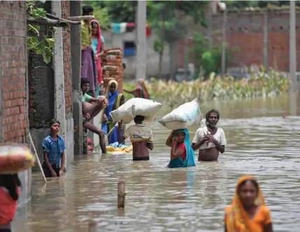  ?? Photo: AFP ?? Indian residents wade along a flooded street carrying their belongings following heavy monsoon rains at Sitamarhi district, in the Indian state of Bihar, on July 17, 2019.