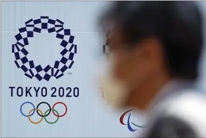  ?? EUGENE HOSHIKO — THE ASSOCIATED PRESS ?? A man wearing a protective face mask walks near the Tokyo 2020 Olympics on Thursday in Tokyo.