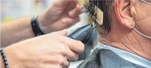  ?? FOTO: HARALD TITTEL/DPA ?? Ein Bild aus der Vor-Lockdown-Ära: Ein Friseur schneidet einem Kunden die Haare. Angesichts des verlängert­en Lockdowns sehen viele Friseure ihre Existenz bedroht.