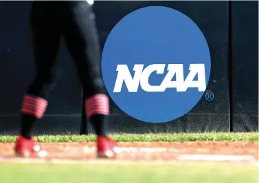  ?? Aaron M. Sprecher/Associated Press file photo ?? ■ An athlete stands near a NCAA logo on April 19 during a softball game in Beaumont, Texas. The NCAA will now allow college athletes to earn money without violating amateurism rules. A California law set to take effect in 2023 would make it illegal for NCAA schools in the state to prevent athletes from signing personal endorsemen­t deals.