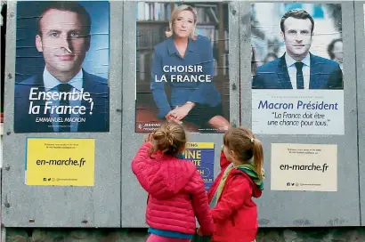  ?? AP ?? Children walk past election campaign posters for Emmanuel Macron and Marine Le Pen, in Osses, southweste­rn France. —