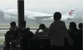  ?? — AP ?? Safety priority: Passengers wait for their flight as a China Eastern aircraft takes off from the runway of Baiyun Airport in Guangzhou province. The company is working with global regulators to safely return the 737-8 and 737-9 to service worldwide.