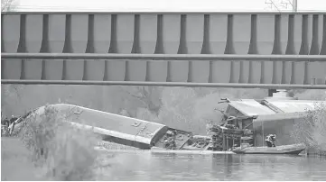  ??  ?? Rescuers work at the scene where a high-speed TGV train coach and engine carriage lie in a canal in Eckwershei­m near Strasbourg, northeaste­rn France. — AFP photo