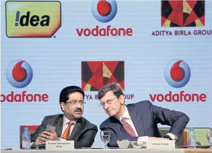  ??  ?? Kumar Mangalam Birla, left, chairman of Aditya Birla Group, speaks to Vittorio Colao, CEO of Vodafone Group Plc, during a news conference in Mumbai yesterday.